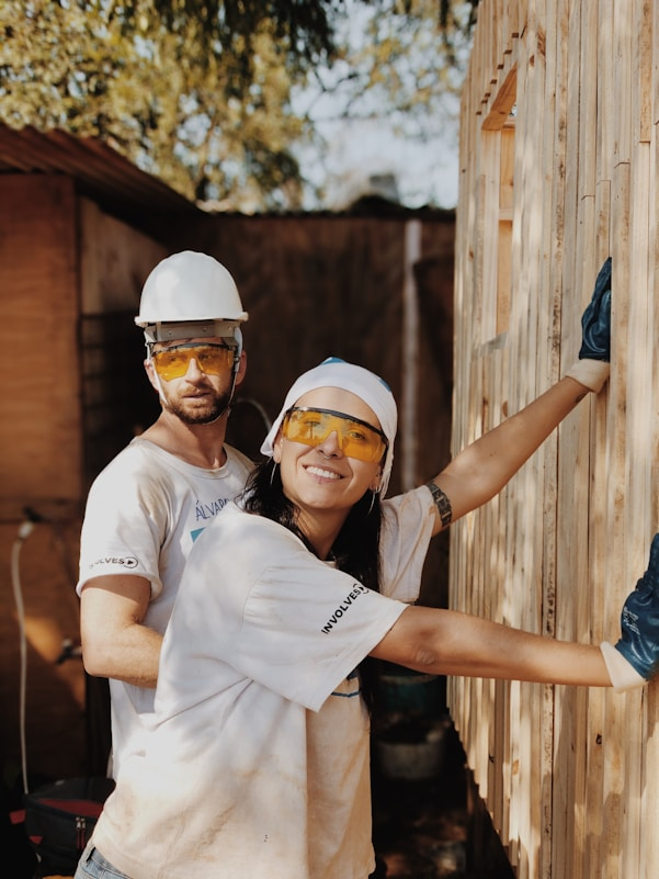 Two people in hard hats working on a construction site.