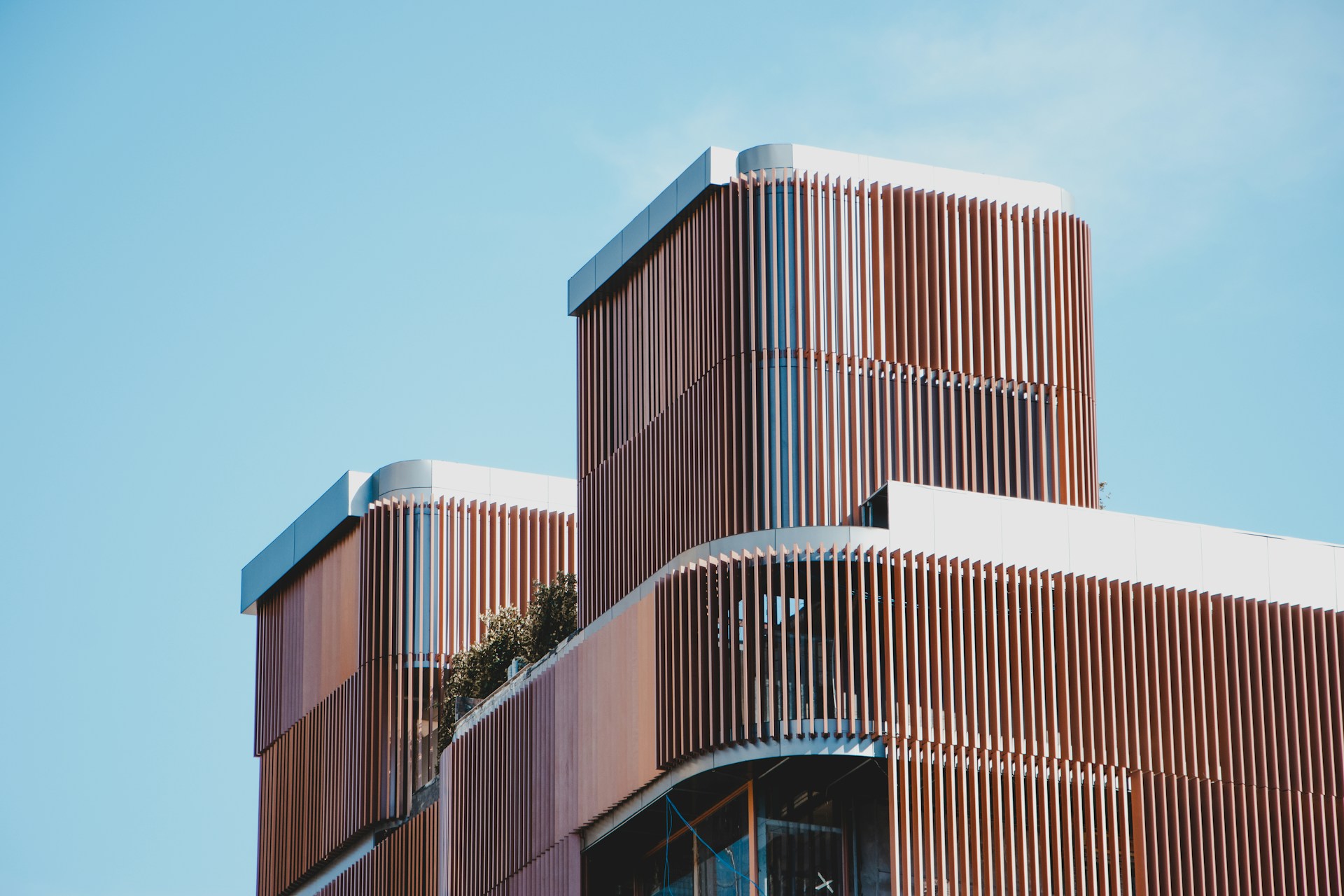 The upper portion of a modern-looking house with timber screening along the outside, with blue sky in the background.