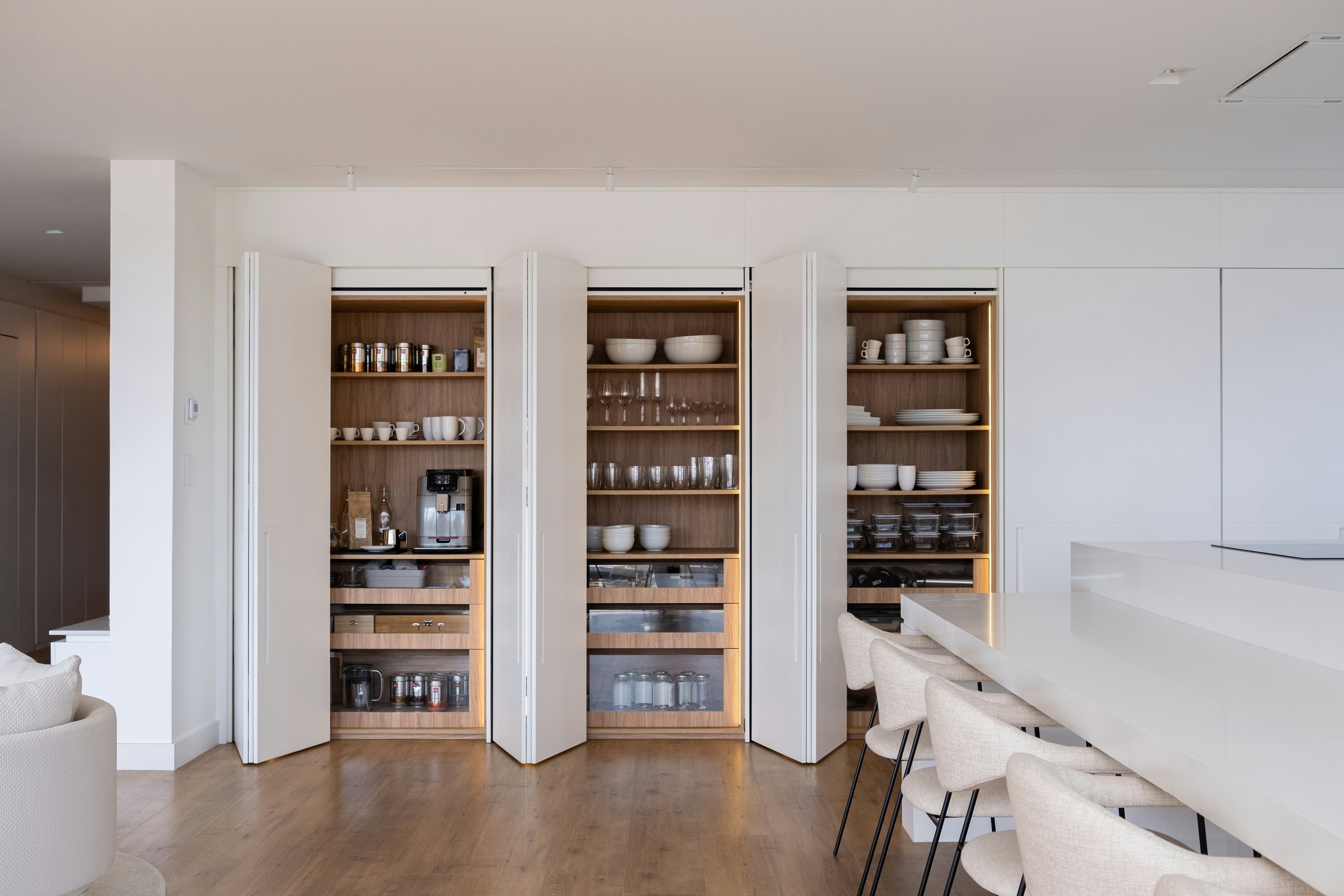 Three built in cabinets holding dishwear and other items in a kitchen.